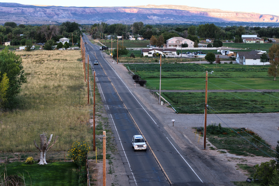 Drone photo of B ½ Road near 31 Road with fields and houses on either side of the road, and the Colorado National Monument in the background.
